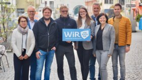 Der gesamte Vorstand der WiR Alpbachtal, 3 Frauen und 5 Männer, stehen im Stadtzentrum von Rattenberg und in der Mitte wird eine blaue Tafel mit der Aufschrift "WiR Alpbachtal" gehalten. | © WiR Alpbachtal